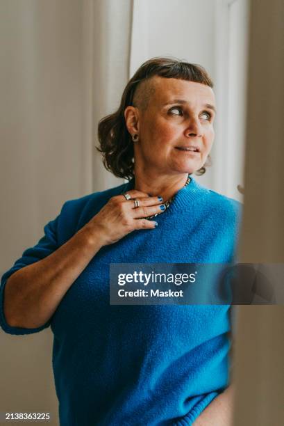 thoughtful mature woman looking over shoulder at home - einzelne frau über 40 stock-fotos und bilder
