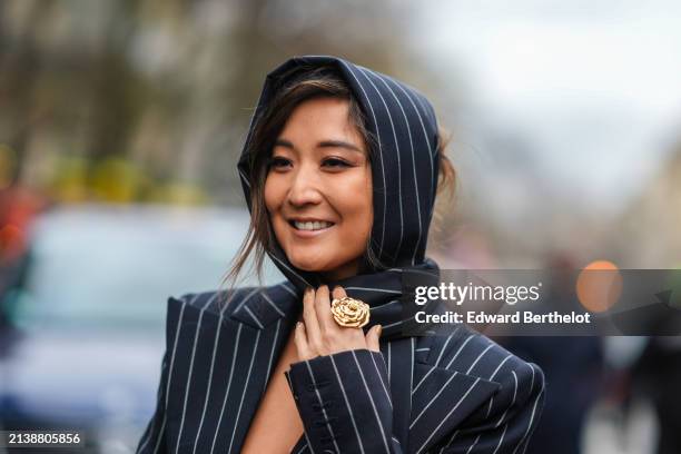 Ashley Park wears a black striped blazer low-neck dress, matching long scarf, outside Nina Ricci, during the Womenswear Fall/Winter 2024/2025 as part...