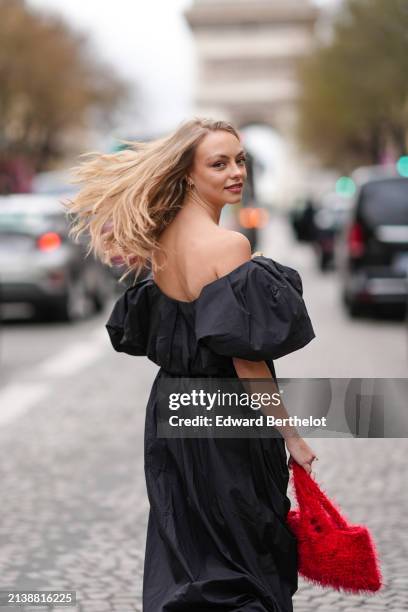 Anouchka Gauthier wears a black long gathered off-shoulders dress with oversized puff sleeves, a red fluffy bag, outside Nina Ricci, during the...