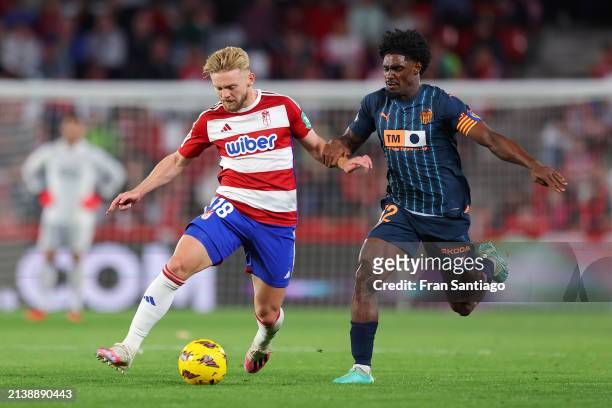 Kamil Jozwiak of Granada CF runs with the ball whilst under pressure from Thierry Correia of Valencia CF during the LaLiga EA Sports match between...