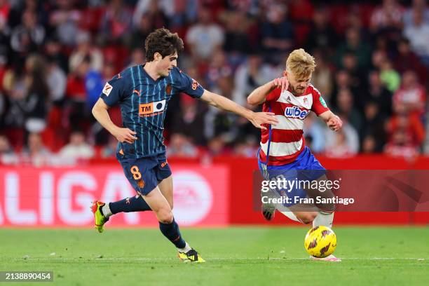 Kamil Jozwiak of Granada CF runs with the ball whilst under pressure from Javi Guerra of Valencia CF during the LaLiga EA Sports match between...