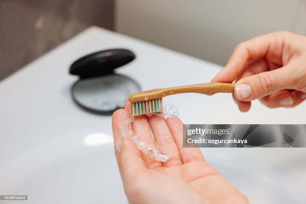 Woman's hand holding invisible aligners.