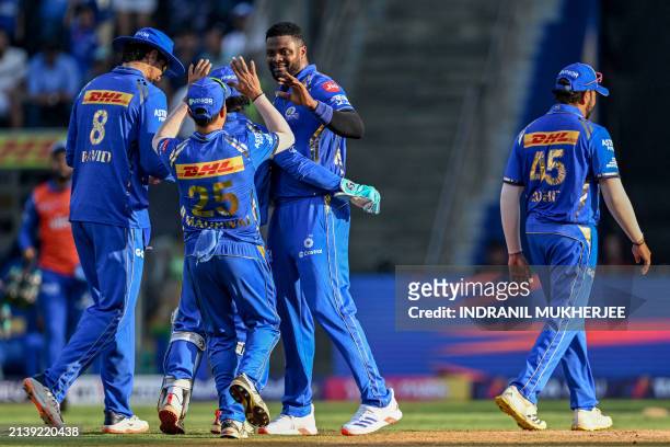 Mumbai Indians' Romario Shepherd celebrates with his teammates after taking the wicket of Delhi Capitals' David Warner during the Indian Premier...