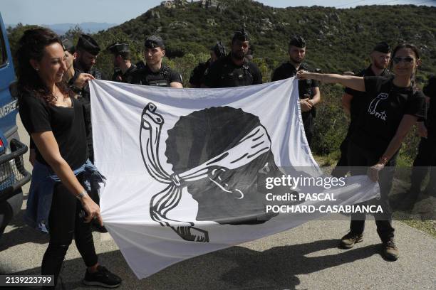 Members and supporters of the Nationalist party Core In Fronte hold a Corsican flag during a rally close nearby the secondary residence of French...