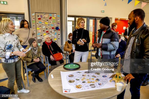 Migrants and volunteers playing a cultural game at La Maison Bakhita, Paris, France.