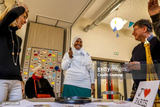 Migrants and volunteers playing a cultural game at La Maison Bakhita, Paris, France.