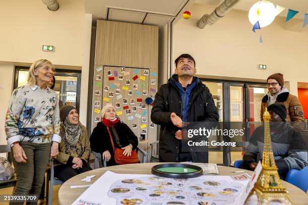 Migrants and volunteers playing a cultural game at La Maison Bakhita, Paris, France.