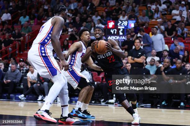 Jimmy Butler of the Miami Heat dribbles the ball against Kyle Lowry and Joel Embiid of the Philadelphia 76ers during the second quarter of the game...