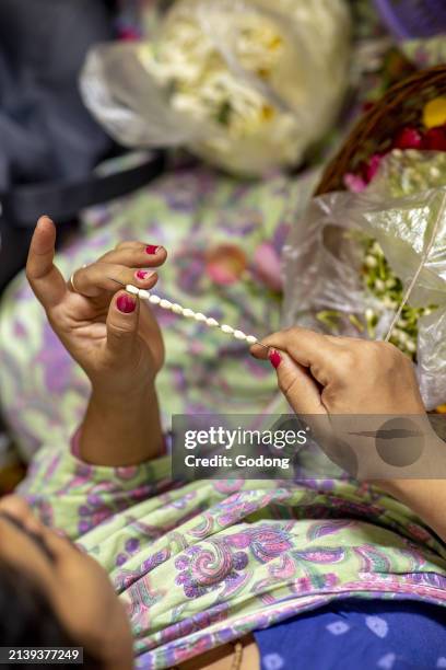 Woman making garlands at ISKCON temple in Juhu, Mumbai, India.