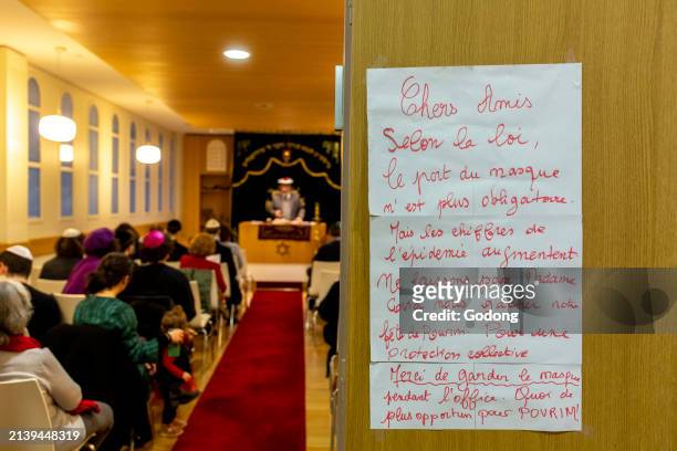 Purim celebration in Beth Yaacov synagogue, Paris, France. Sign recommending wearing face masks.