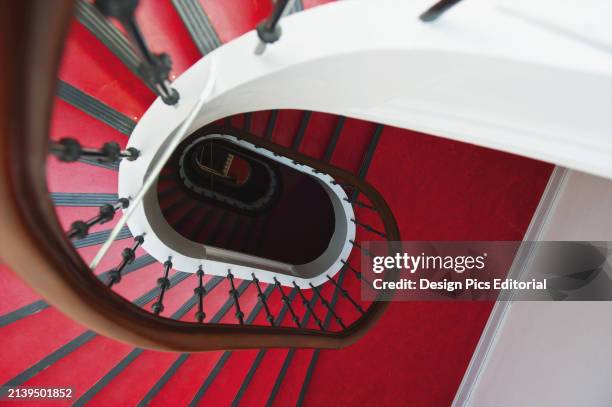 Red Staircase With Brown Handrail and Black Metal Balusters on A White Wall. Hamburg, Germany.