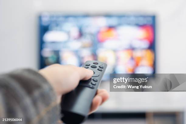 use the remote control to adjust the channel - tv kijken stockfoto's en -beelden