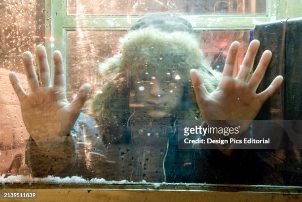 Child With Hands Pressed Against Winter Window