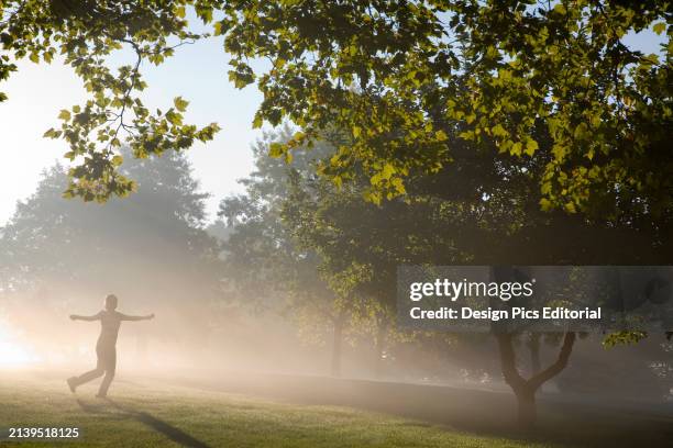 Girl walking through fog and sunlight at sunrise in a park. Portland, Oregon, United States of America.