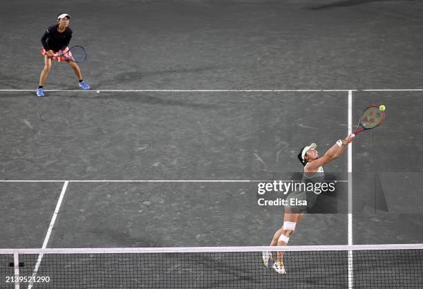 Eri Hozumi of Japan returns a shot as teammate Makoto Ninomiya of Japan looks on during their doubles match against Hao-Ching Chan of Taipei and...