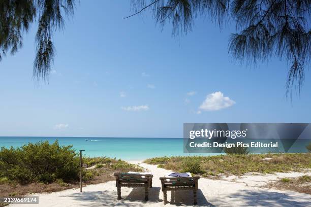 Two Beds Sit In The Shaded White Sand With A View of The Ocean. Vamizi Island, Mozambique.