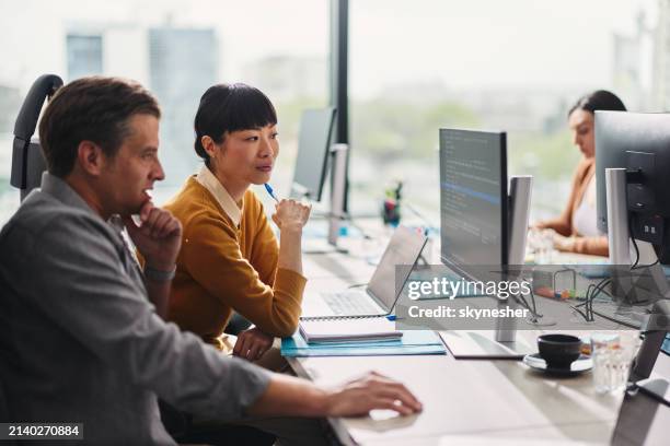 geschäftskollegen, die codes auf dem desktop-pc im büro lesen. - webdesigner stock-fotos und bilder