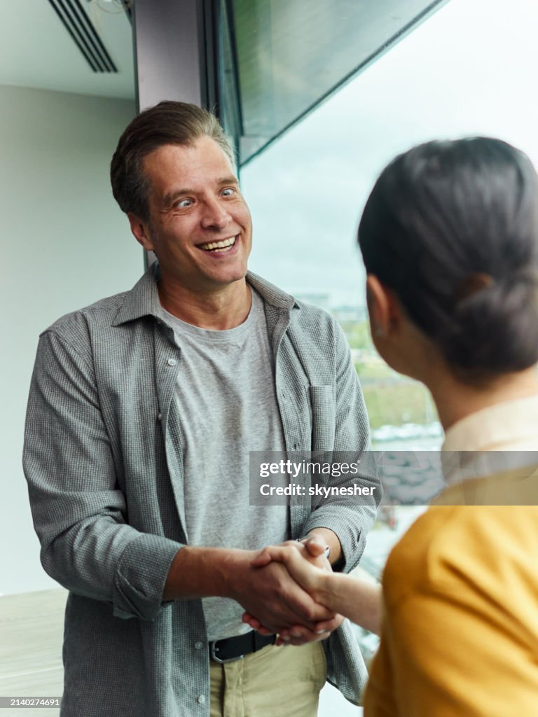 Funny cross-eyed businessman shaking hands with his colleague in the office.
