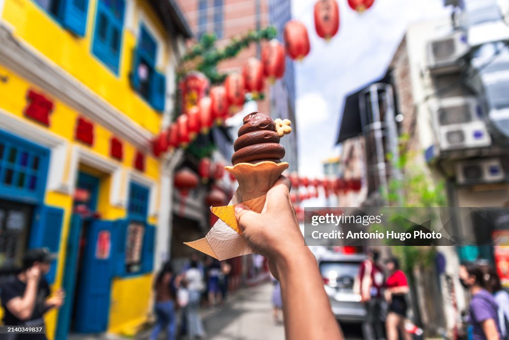 Hand holding a chocolate ice cream in Kuala Lumpur's Chinatown.