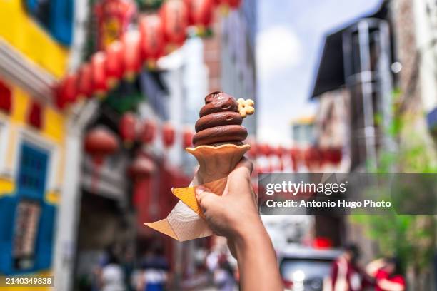 hand holding a chocolate ice cream in kuala lumpur's chinatown. - sorvete chocolate chip - fotografias e filmes do acervo