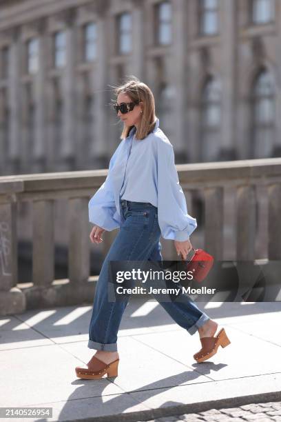 Sonia Lyson seen wearing Saint Laurent black / brown sunglasses, SoSue light blue cotton buttoned oversized shirt, Levi’s dark blue denim straight...
