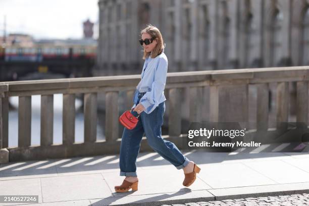 Sonia Lyson seen wearing Saint Laurent black / brown sunglasses, SoSue light blue cotton buttoned oversized shirt, Levi’s dark blue denim straight...