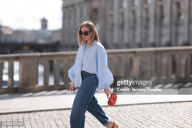 Sonia Lyson seen wearing Saint Laurent black / brown sunglasses, SoSue light blue cotton buttoned oversized shirt, Levi’s dark blue denim straight...