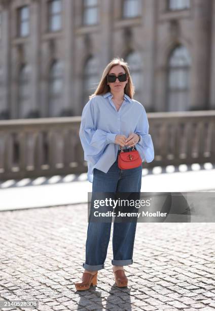 Sonia Lyson seen wearing Saint Laurent black / brown sunglasses, SoSue light blue cotton buttoned oversized shirt, Levi’s dark blue denim straight...