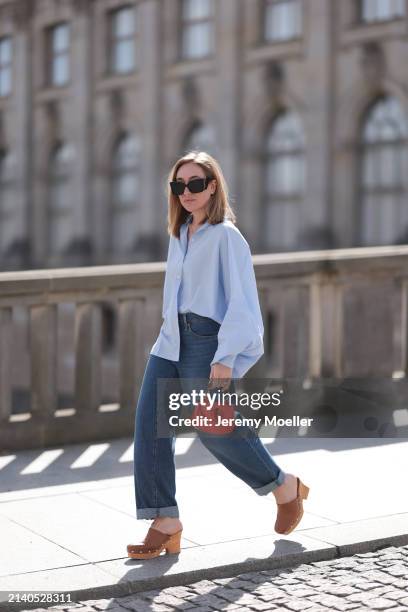 Sonia Lyson seen wearing Saint Laurent black / brown sunglasses, SoSue light blue cotton buttoned oversized shirt, Levi’s dark blue denim straight...