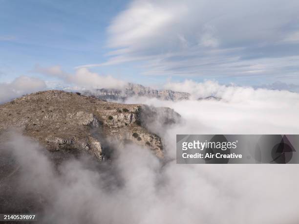 drone image showing a mountainous rocky landscape surrounded by a sea of clouds, alpes-maritimes, france - air france stock pictures, royalty-free photos & images