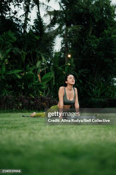 young woman practicing yoga on a lawn - cobra pose stock pictures, royalty-free photos & images