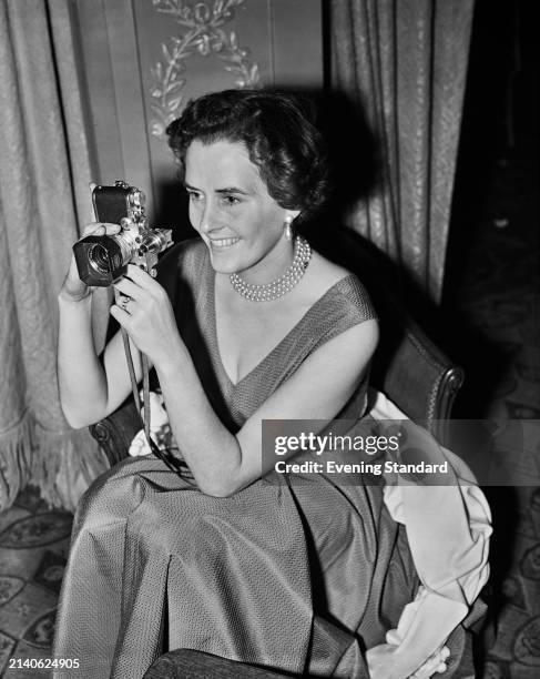 Austrian photographer Inge Moranth holding up her camera, November 30th 1953.
