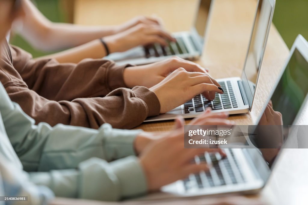 Teenage girls using typing on laptops