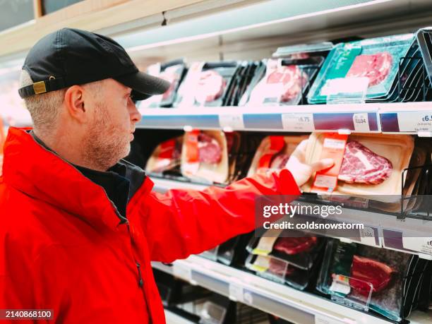 man shopping for beef steak in supermarket aisle - supermarket uk stock pictures, royalty-free photos & images