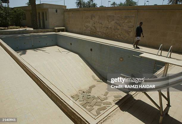 An Iraqi man walks 19 June 2003, past a mural decorating a wall surrounding a swimming pool Iraqi men walk 19 June 2003, in the home of toppled...