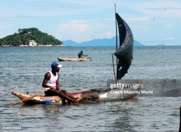 Fishermen in their canoes on Lake Malawi as people swim around the shallow waters at Senga Bay, Malawi.