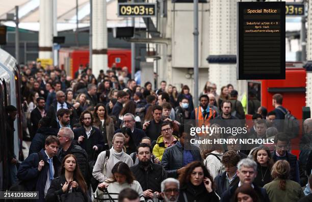 Commuters walk along a packed platform after a single train arrived during the morning rush hour, at Waterloo Station in London on April 8 as train...