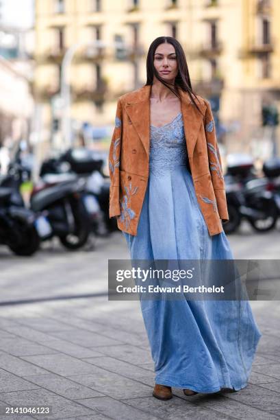 Paola Turani wears a brown jacket with floral embroidery details, a blue low-neck denim dress with lace details, outside Ermanno Scervino, during the...
