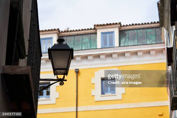side view of a retro-style lantern on the exterior wall of a house with no people around. - vintage embellishment stock pictures, royalty-free photos & images