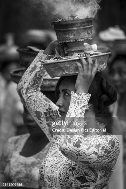Young Woman At A Religious Ceremony Carrying A Smoking Offering on Her Head. Bali, Indonesia.