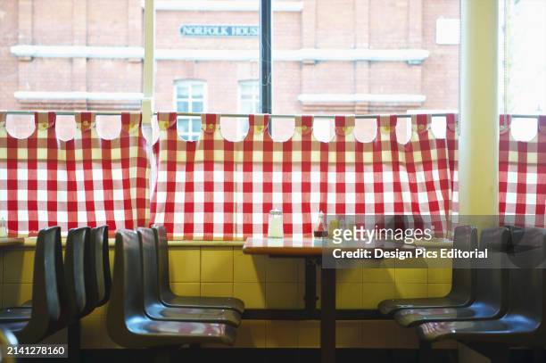 Restaurant With Red and White Checkered Curtains on The Window and A Yellow Wall. London, England.