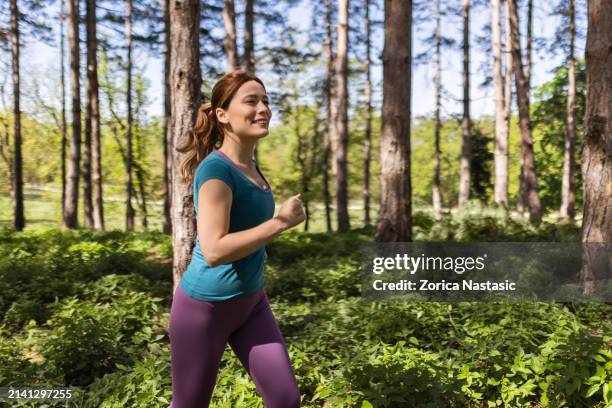 joven atleta femenina abrazando el viaje de trote - corredora de footing fotografías e imágenes de stock