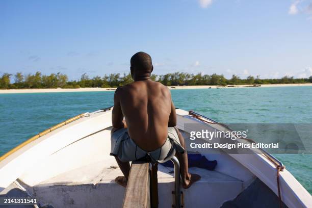 Man Sits on His Boat on The Tranquil Turquoise Indian Ocean With A View of The White Sand Beach. Vamizi Island, Mozambique.