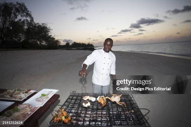 Chef Cooks on A Grill on The Beach at Sunset. Vamizi Island, Mozambique.