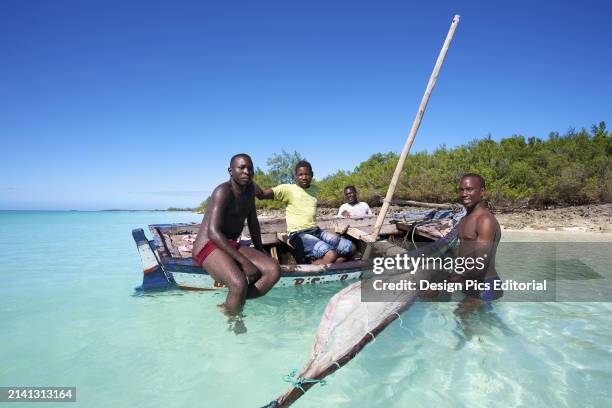 Men Sitting In An Old Wooden Sailboat Close To The Shore. Vamizi Island, Mozambique.