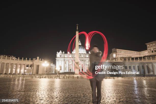 Woman Stands With A Red Light Trail In The Shape of A Heart In St. Peter's Square. Rome, Lazio, Italy.