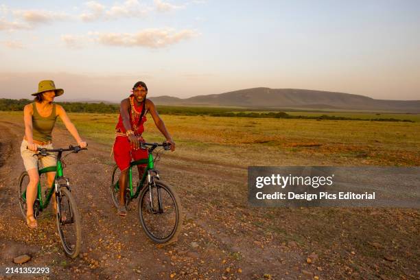 Tourist with guide on mountain bike safari in the Maasai Mara National Reserve, Kenya, Africa. Maasai Mara, Kenya.