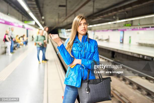 beautiful woman holding a handbag as she waits impatiently for her train to arrive. - ongeduldig stockfoto's en -beelden