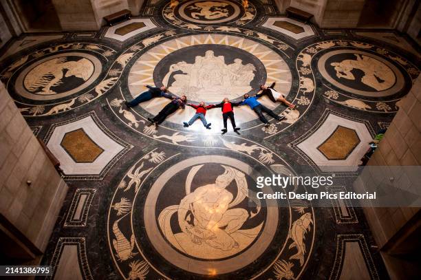Tour group lays in a row on the decorative Rotunda floor in the Nebraska State Capitol and looks up to admire the ceiling. Lincoln, Nebraska, United...