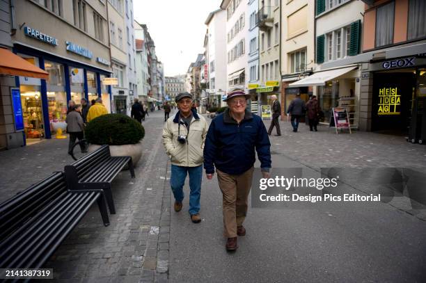 Two senior men stroll along a city street in Zurich, Switzerland. Zurich, Switzerland.